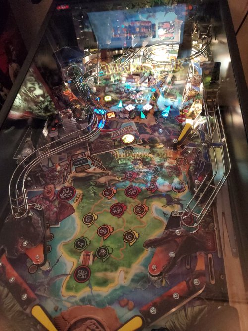 A top-down view of a colorful pinball machine featuring various lights, ramps, and themed artwork.
