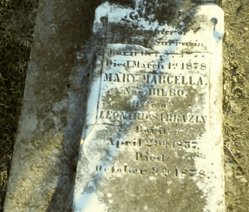 A weathered gravestone with inscriptions for Mary Marcella and Leonidas Brienzin, detailing their birth and death dates.