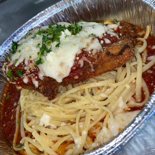A foil container filled with spaghetti topped with marinara sauce, a breaded chicken cutlet, and melted cheese.