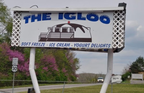 Sign for "The Igloo" featuring soft freeze, ice cream, and yogurt delights, set against a cloudy sky.