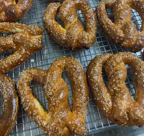 Freshly baked pretzels with a golden-brown crust and coarse salt, arranged on a cooling rack.