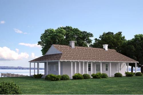 A white house with a brown roof, surrounded by greenery, near a body of water under a clear blue sky.