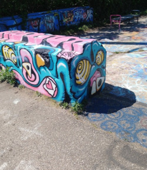 Colorful graffiti art on a concrete block, featuring abstract shapes and vibrant patterns in pink, blue, and yellow.