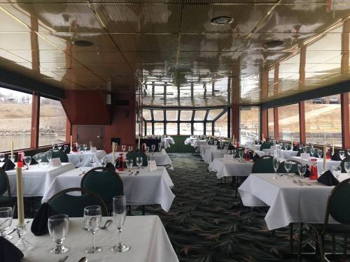 Interior of a dining area with white tablecloths, candles, and large windows overlooking a scenic view.