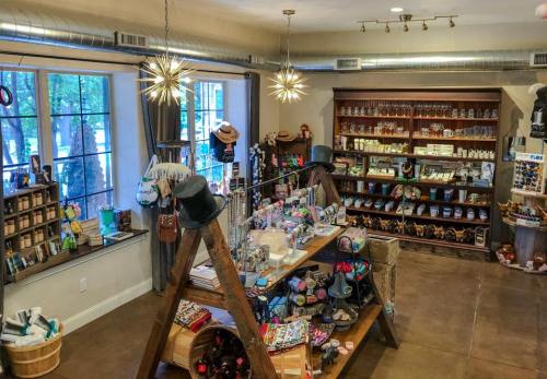 A cozy shop interior featuring wooden displays filled with various gifts and accessories, with large windows and stylish lighting.