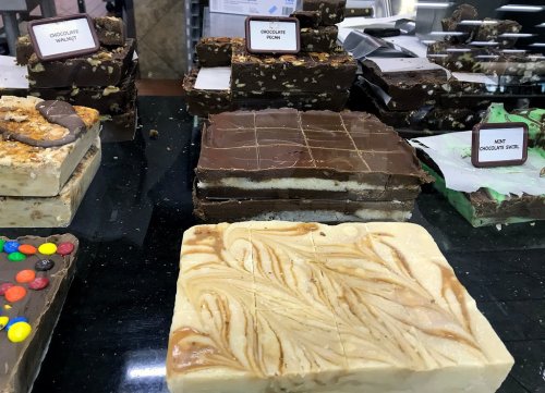 A display of various fudge flavors, including chocolate walnut, chocolate pecan, and swirled vanilla fudge.