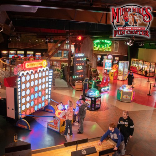 A vibrant indoor arcade with various games and families enjoying their time at Miner's Mike's Fun Center.