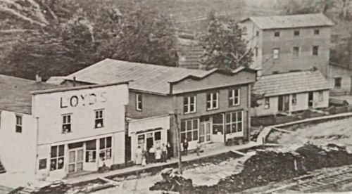 Historic black-and-white photo of a small town with buildings, including a store labeled "Loyds."