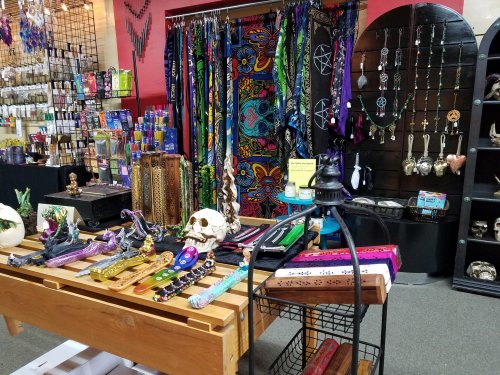 A vibrant shop display featuring colorful scarves, jewelry, and mystical decor on wooden tables and shelves.