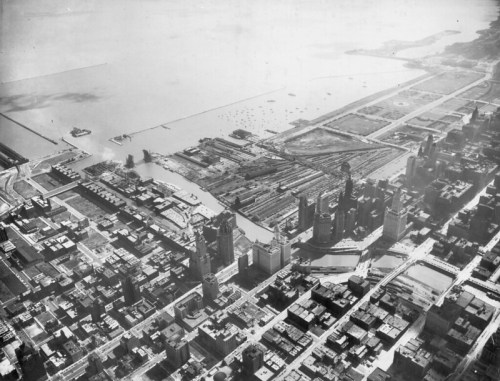 Aerial view of a cityscape with buildings, a river, and a waterfront area, showcasing urban development and landscape.
