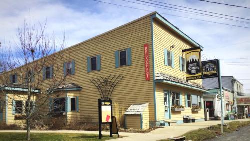 A yellow two-story building with blue trim, featuring a sign for a brewery and outdoor seating area.
