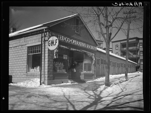 A historic co-operative society building with a "Gulf" sign, surrounded by snow and trees on a winter day.