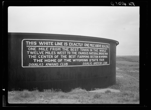 Sign on a cylindrical structure reads about its location and the Wyoming State Fair, with a humorous tone.