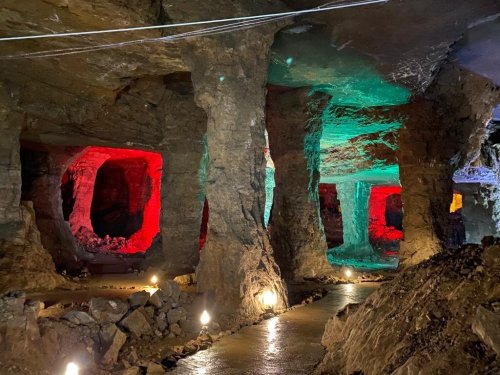 Colorful illuminated cave interior with rock formations and a pathway, showcasing red and green lighting effects.