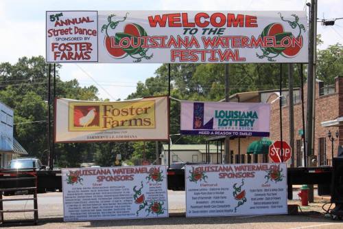 A festival banner welcomes visitors to the Louisiana Watermelon Festival, featuring sponsor logos and event details.