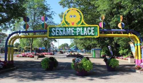 Colorful entrance to Sesame Place, featuring a large sign with Big Bird and vibrant flower planters.