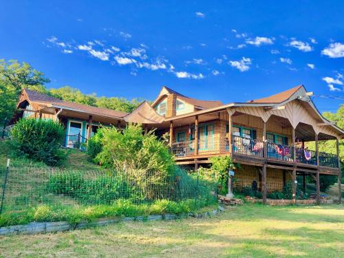 A charming wooden house on a hillside, surrounded by greenery and under a bright blue sky with scattered clouds.