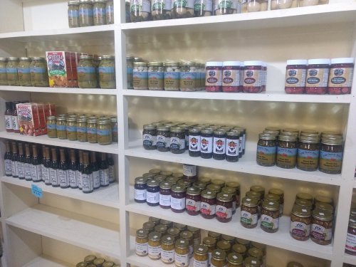 Shelves filled with various jars and bottles of sauces, jams, and preserves in a well-organized display.