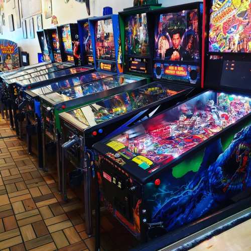 A row of colorful pinball machines lined up in a game room, showcasing various designs and themes.