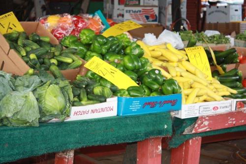 A vibrant display of fresh vegetables, including cucumbers, peppers, squash, and lettuce, at a market stall.