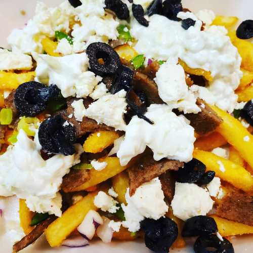 A plate of fries topped with olives, cheese, green onions, and a creamy sauce.