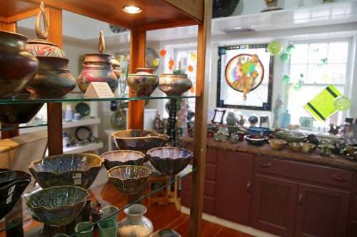 A display of colorful pottery and glass art in a bright, inviting gallery setting.