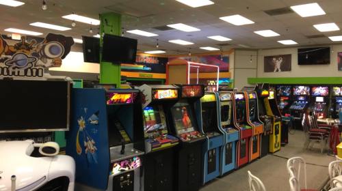 A colorful arcade filled with various vintage arcade game machines and bright lighting.