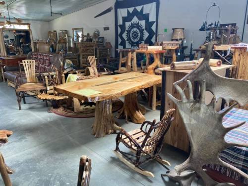 A rustic furniture showroom featuring unique wooden tables, chairs, and decor with a cozy, artistic atmosphere.