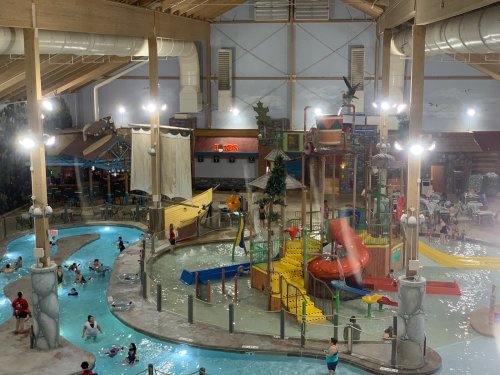 Indoor water park featuring slides, pools, and play structures, with families enjoying the water activities.