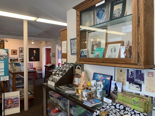 A cozy museum display featuring glass cabinets with memorabilia, photos, and various artifacts on tables.