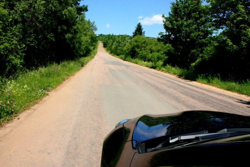 A view of a winding road surrounded by greenery under a clear blue sky.