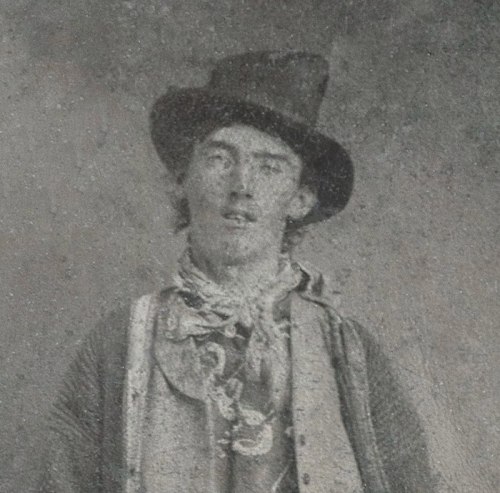A vintage portrait of a young man wearing a top hat and scarf, with a serious expression.