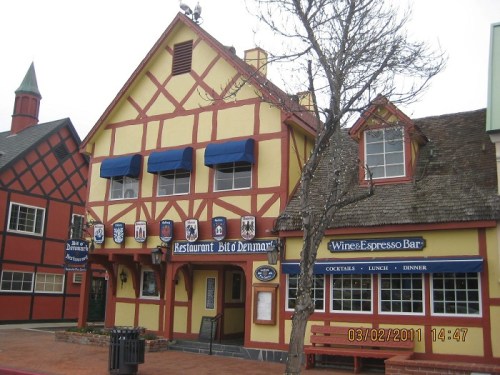A colorful, Tudor-style building housing a restaurant and wine bar, with blue awnings and decorative signage.