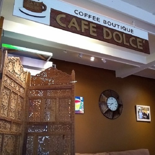 A cozy coffee boutique named "Café Dolce" with a decorative wooden screen and wall art in a warm-toned interior.
