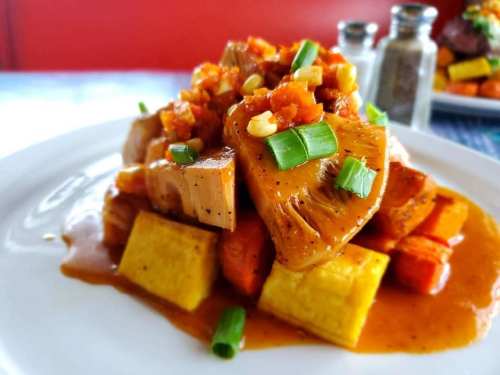 A colorful plate of sautéed vegetables topped with a savory sauce and garnished with green onions.
