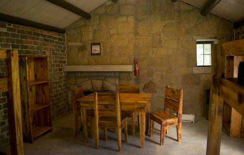Cozy interior of a rustic cabin featuring wooden furniture, a fireplace, and stone walls.