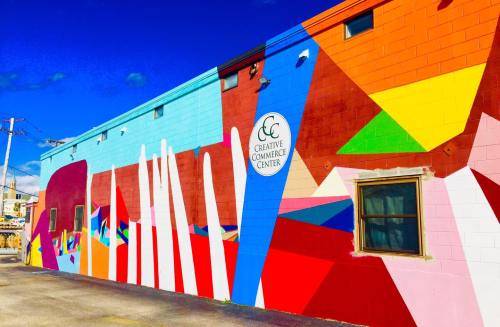 Colorful mural on the side of a building featuring geometric shapes and the text "Creative Commerce Center."