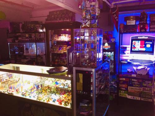 A colorful display of collectibles and toys in a dimly lit shop, with glass cases and shelves filled with various items.