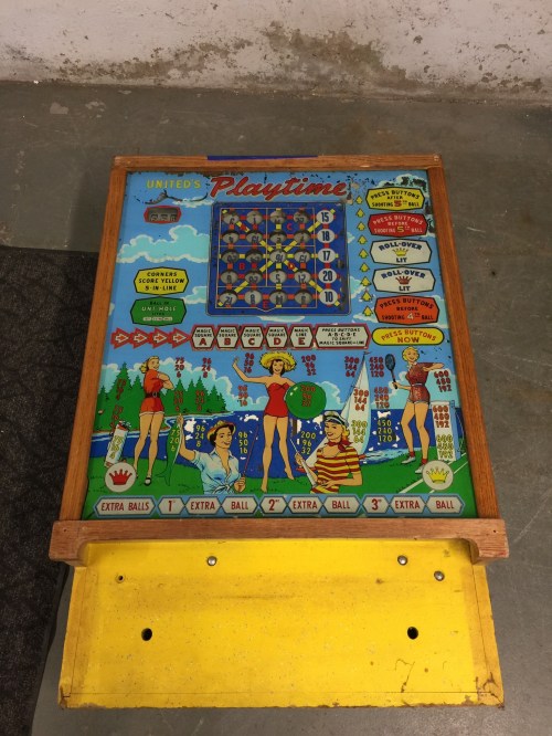 A vintage pinball machine with colorful graphics featuring women in swimsuits and various scoring elements.