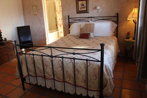 Cozy bedroom featuring a wrought iron bed, floral bedding, a lamp, and warm-toned walls.