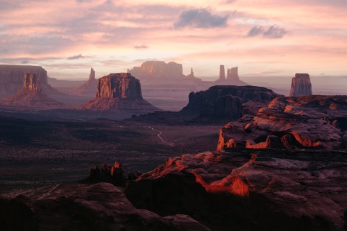 A stunning desert landscape at sunset, featuring towering rock formations and a colorful sky.