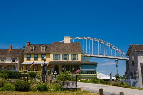 Historic houses with colorful facades under a blue sky, featuring a large bridge in the background.