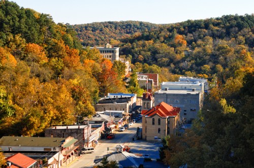 A scenic view of a small town surrounded by autumn-colored trees and rolling hills.