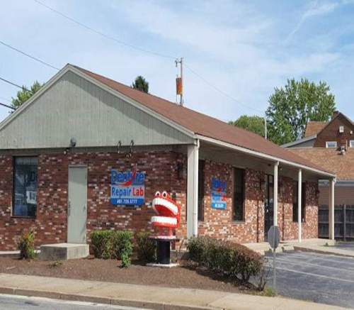 A brick building with a sign for "Dear Tire Repair Lab" and a whimsical red and white sculpture outside.