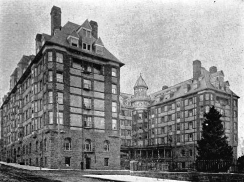 Historic brick building with multiple stories, gabled roofs, and a central tower, surrounded by a snowy landscape.