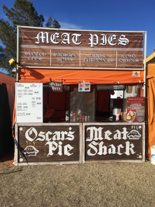 A food stall named "Oscar's Pie Meat Shack" selling meat pies, sausage rolls, and apple turnovers at an outdoor event.