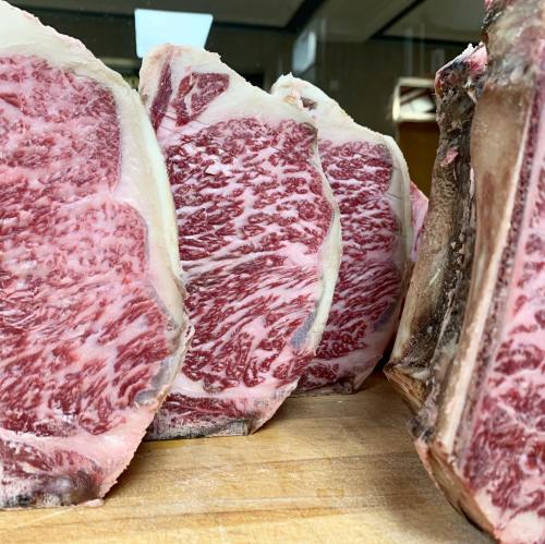 Close-up of marbled beef cuts displayed on a wooden surface, showcasing rich fat distribution and texture.