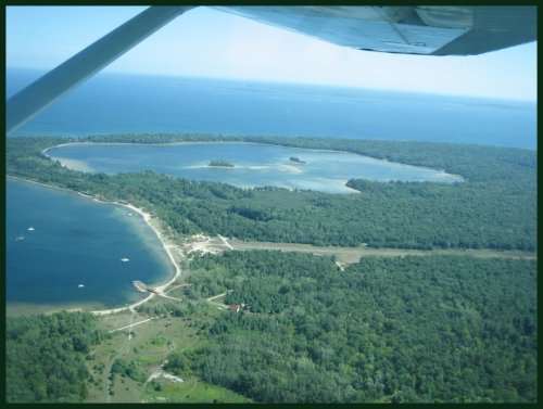 Aerial view of a lush green landscape with lakes and islands, bordered by a blue body of water.
