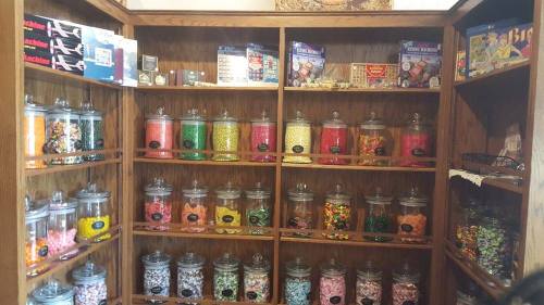 A wooden display cabinet filled with colorful jars of various candies and sweets.