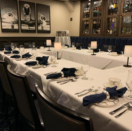 Elegant dining setup with white tablecloths, navy napkins, and glassware in a sophisticated restaurant setting.